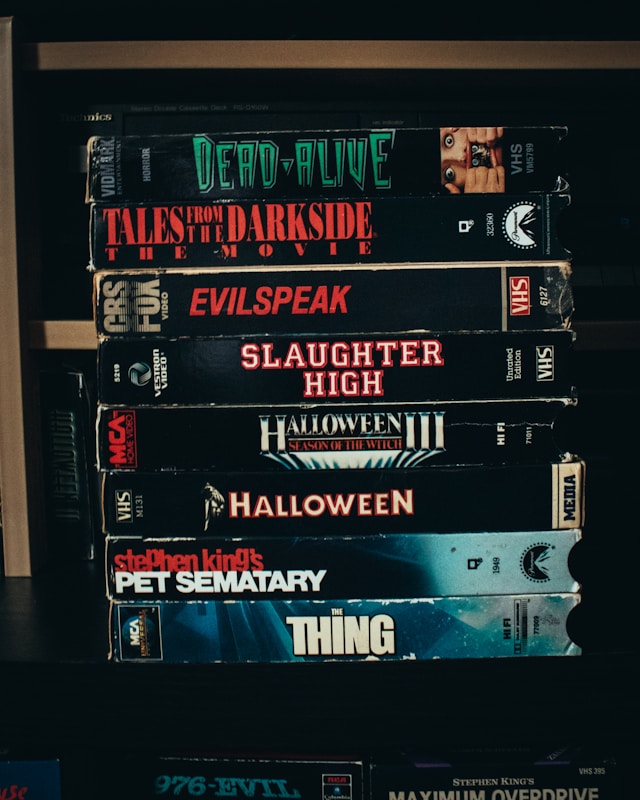 Picture of a bookshelf with stacked VHS horror movies.
